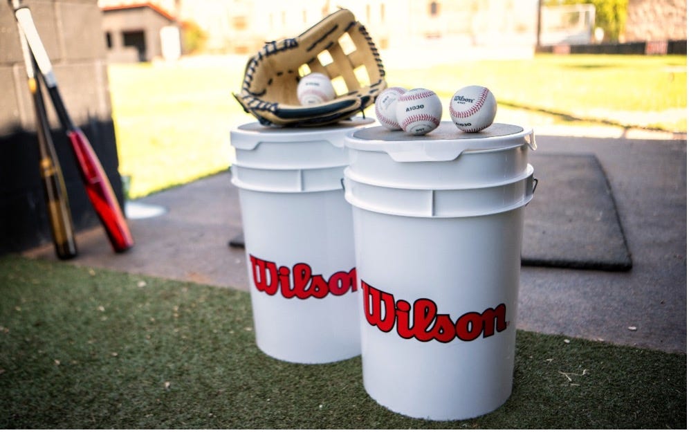 A buckets with baseballs and gloves on top of it
      
      Description automatically generated