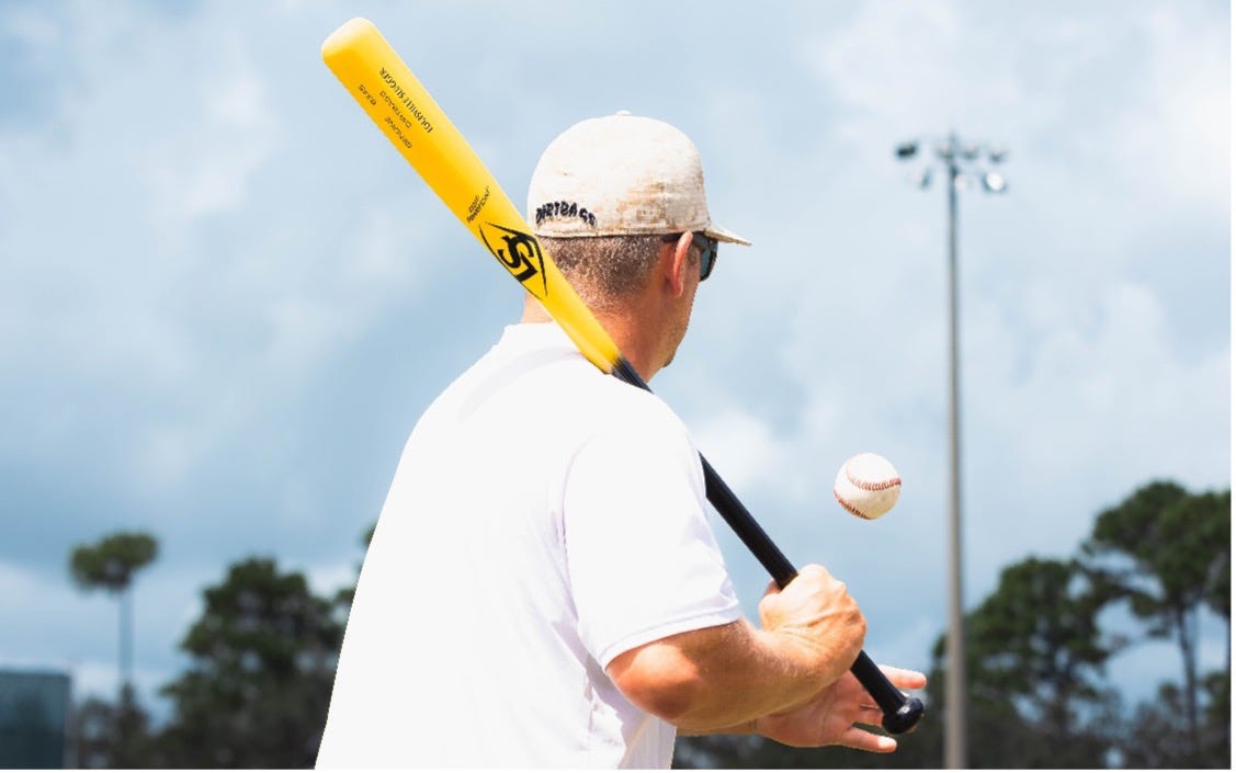 A person holding a baseball bat and ball
      
      Description automatically generated